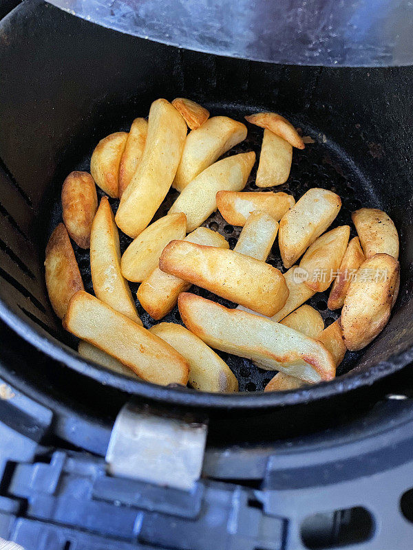 在空气炸锅里炸出的金黄色、新鲜酥脆的薯条/大块薯条，是零食烹饪的更健康的选择，从高处俯瞰